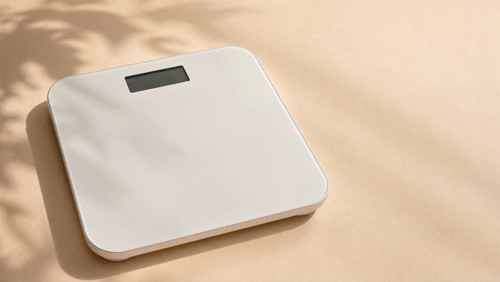 Modern minimalist white digital bathroom scale on cream backdrop