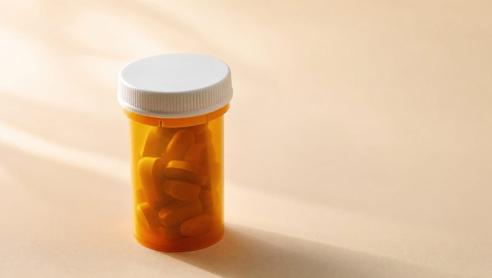 Amber prescription bottle with white cap on a clean background
