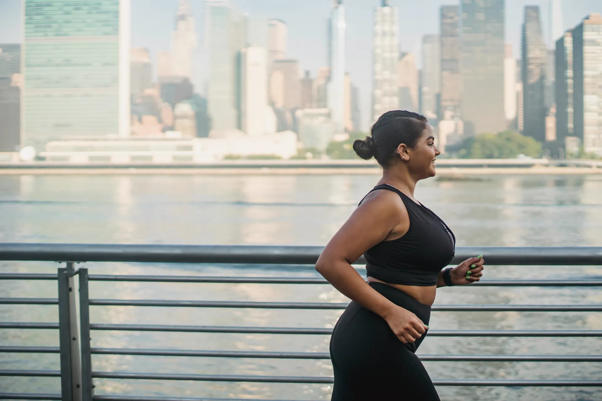 Woman running outdoors along waterfront with city skyline